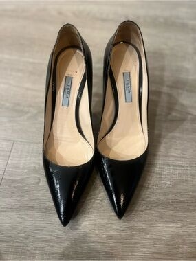 Prada Black Patent Saffiano Leather Pumps feature a glossy finish, pointed toe